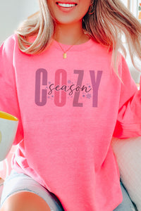 a woman sitting on a couch wearing a pink sweatshirt